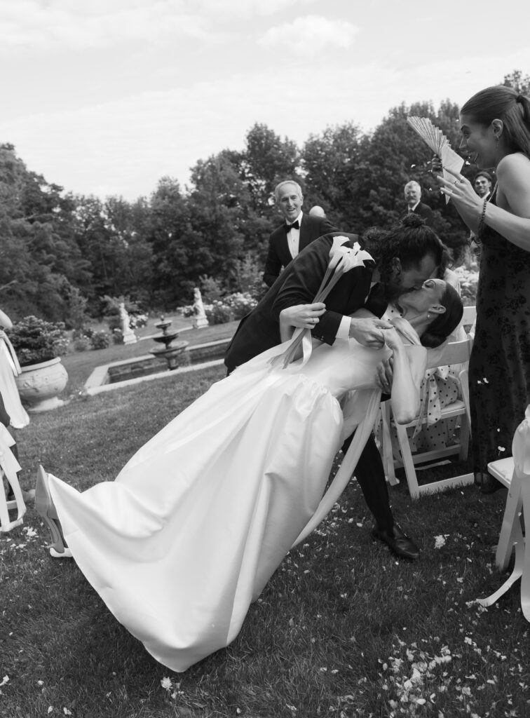 bride and groom dipping and kissing at end of aisle
